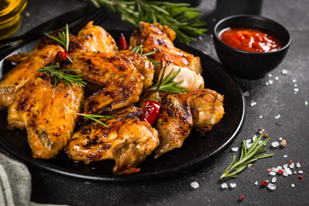 Grilled chicken wings with spices in black plate.