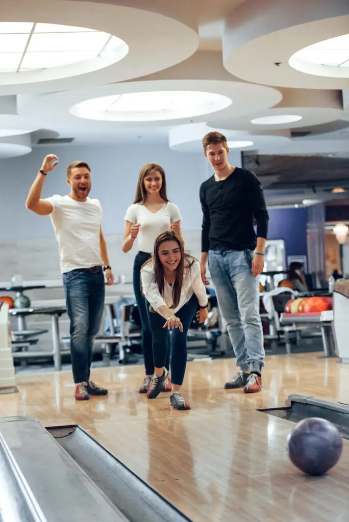 Come on, do a strike. Young cheerful friends have fun in bowling club at their weekends.