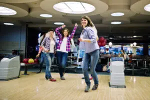 Group of girls having fun and play bowling at hen party.